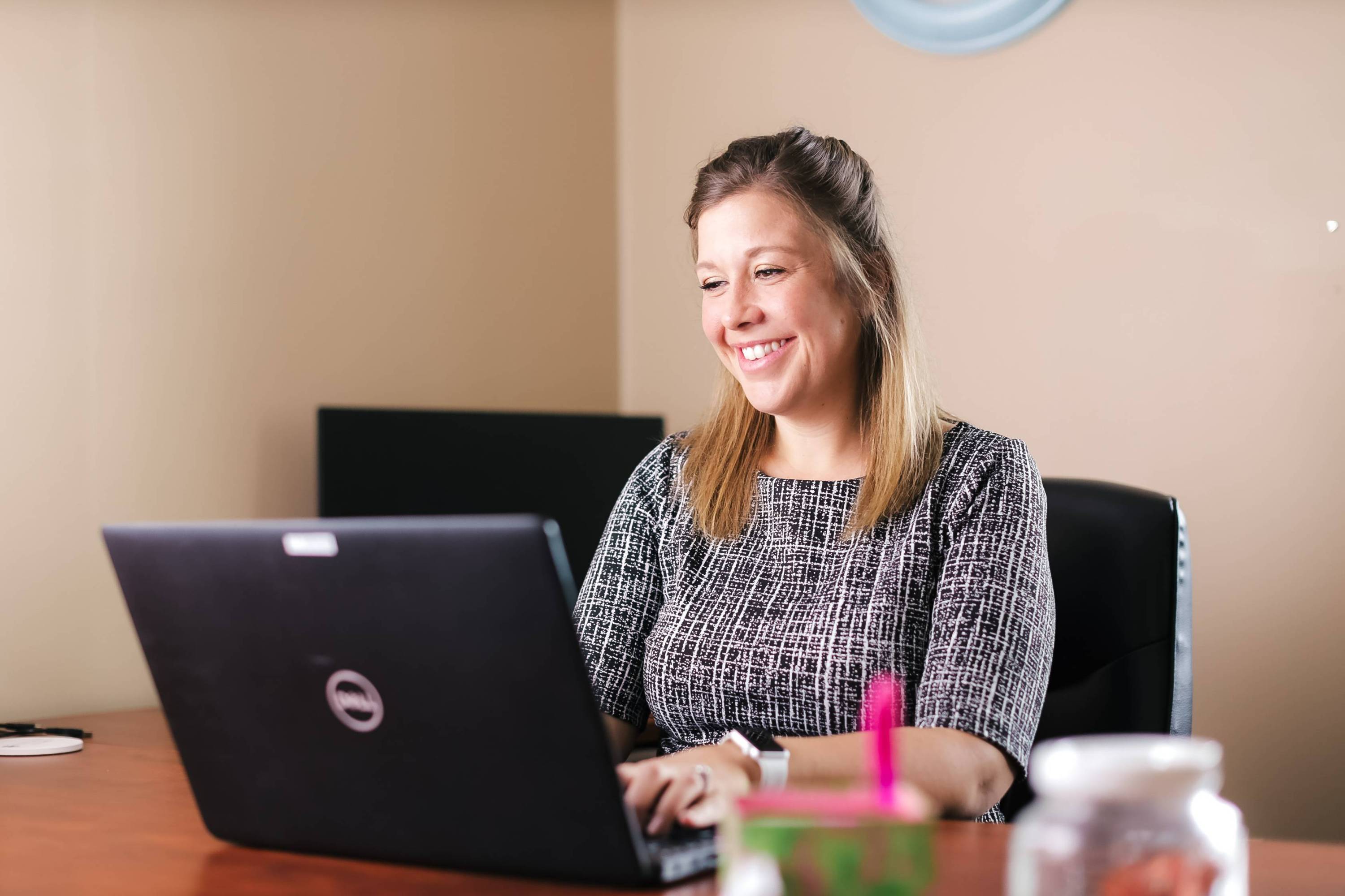 woman smiling at laptop at a desk