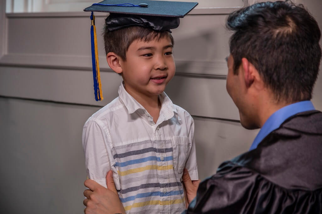 dad puts graduation cap on son