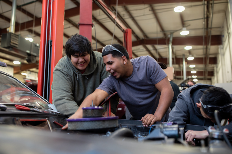 three male students working on vehicle
