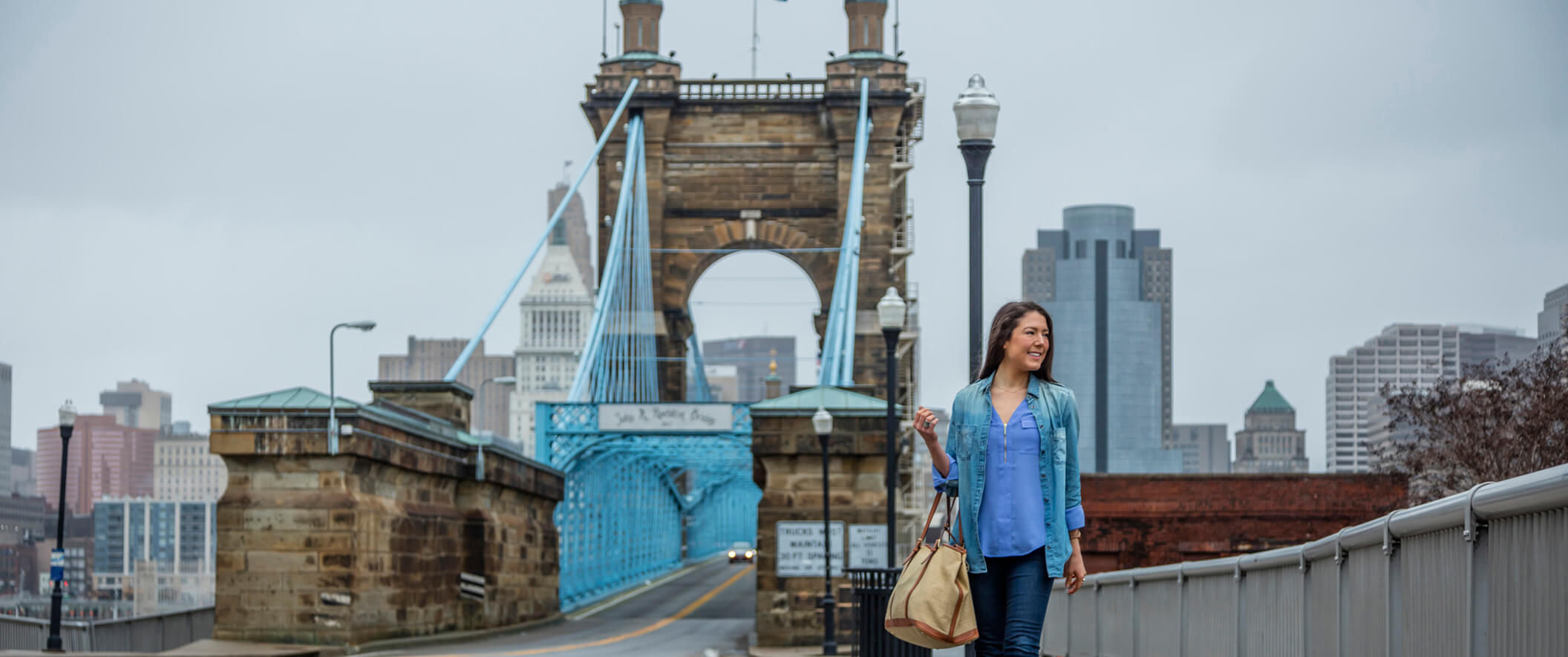 girl walking on bridge with purse