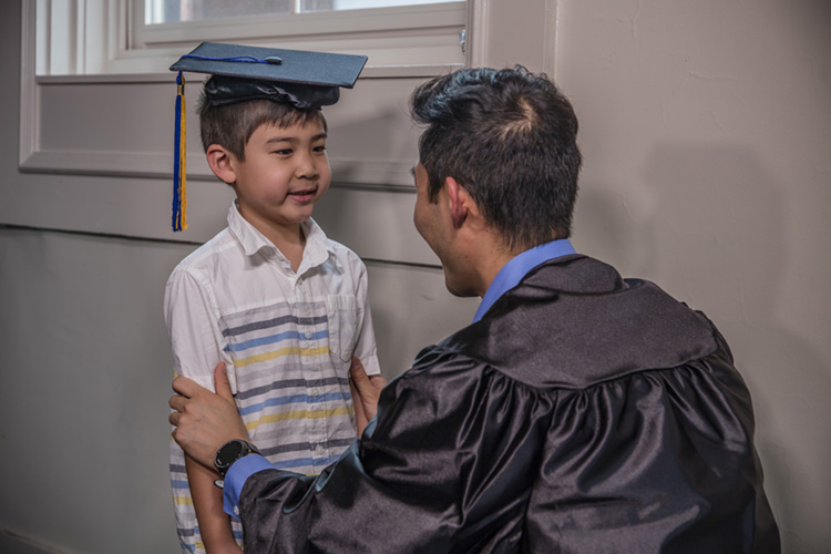 father and son looking at each other while wearing cap and gown