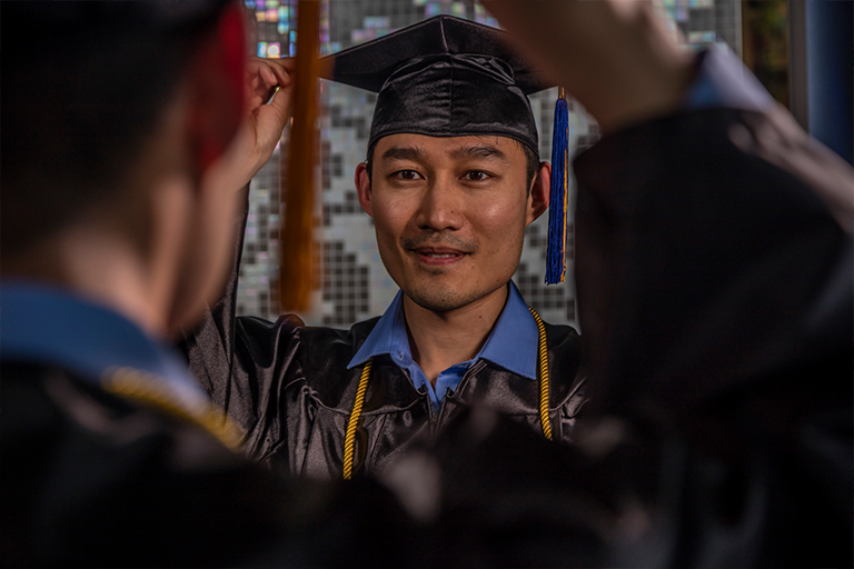 student looking in mirror with cap and gown