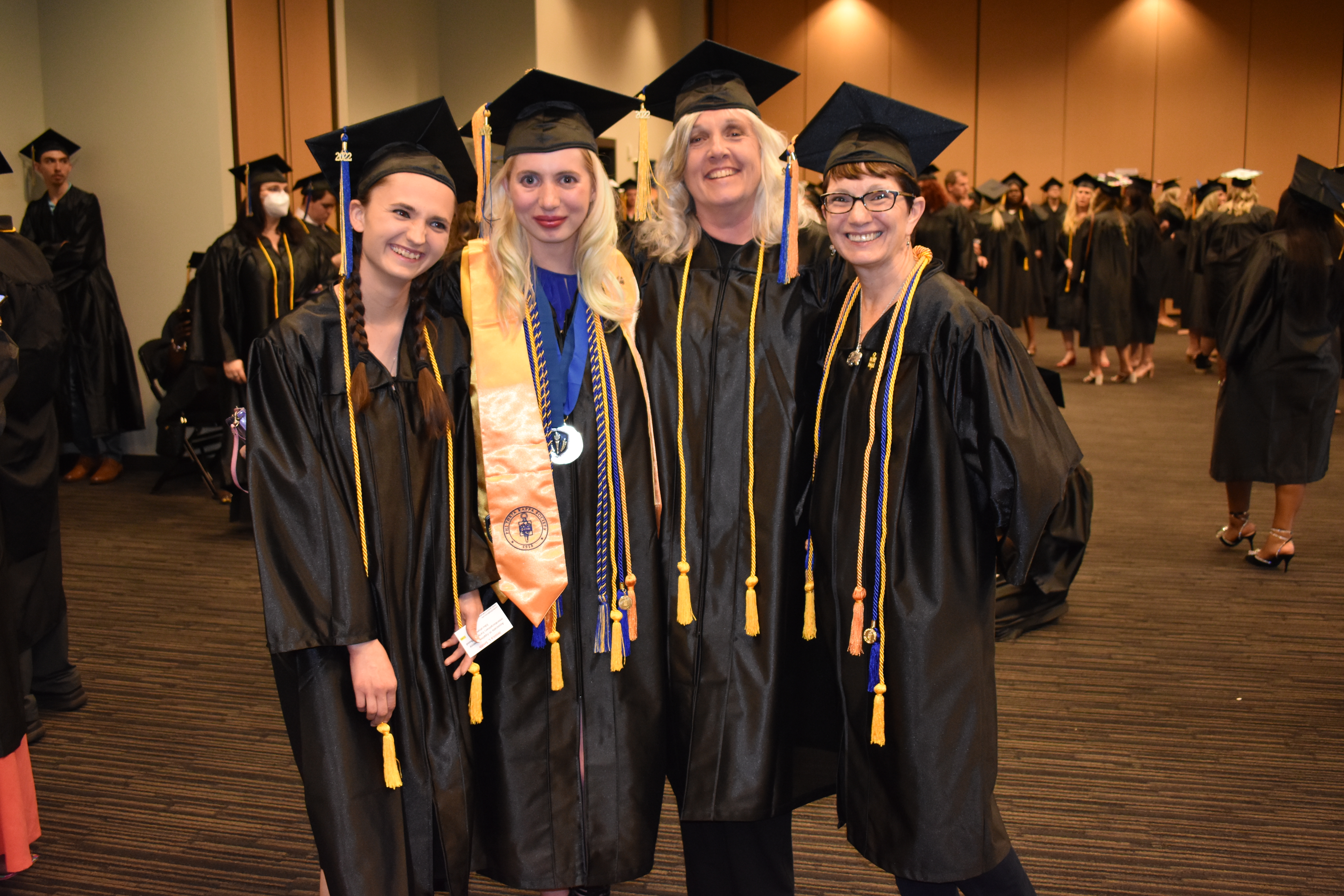 2 students in caps and gowns before graduation.