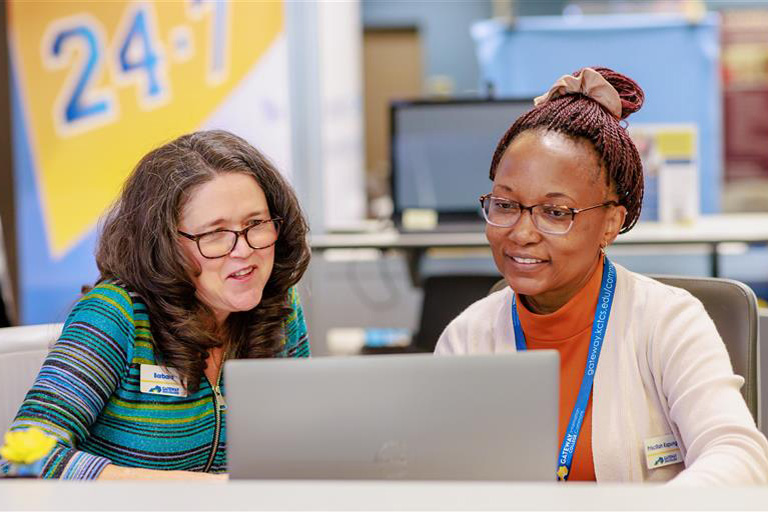 woman sitting at information commons desk with student in front