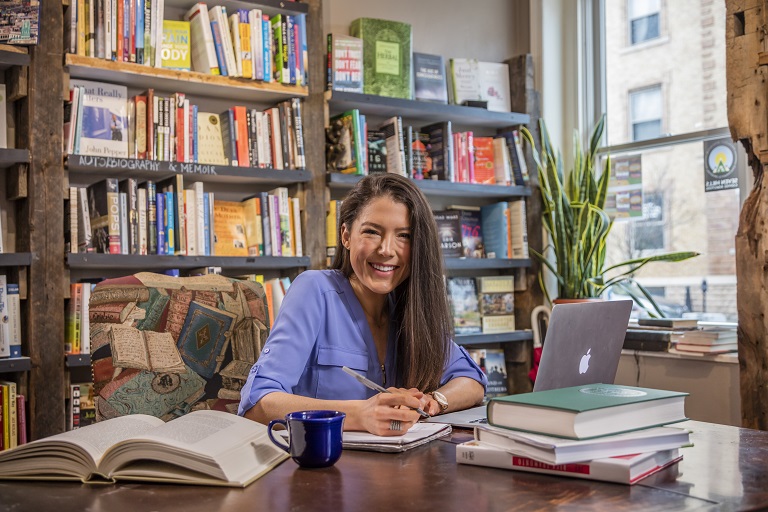 female student sitting at table with her computer doing homework in a coffee shop