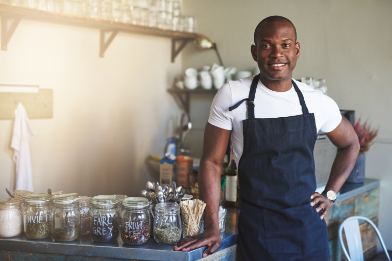 man leaning on kitchen table with tea spices next to him