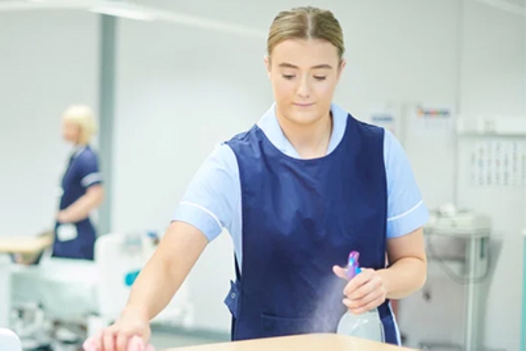 woman spraying a table and wiping it