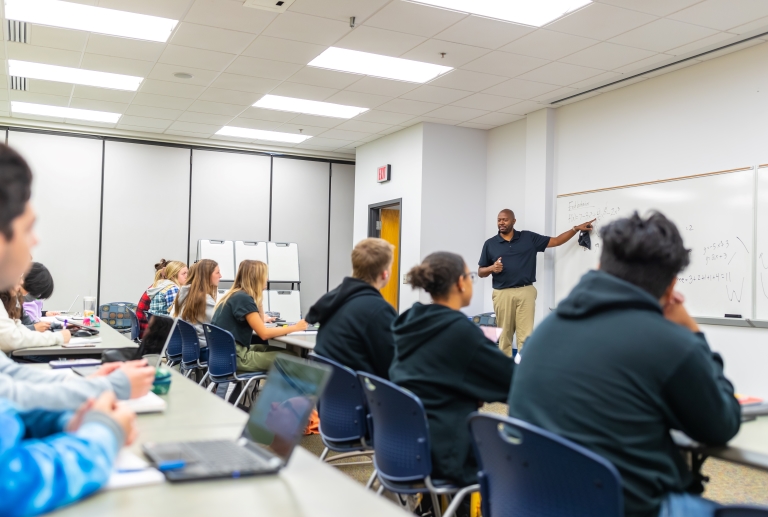 students sitting in a classroom, listening to an instructor