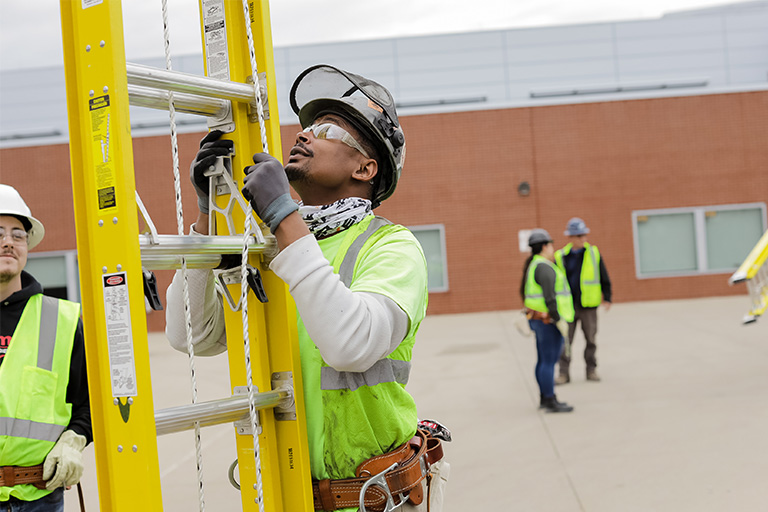 Gateway lineworker student in uniform holding a ladder