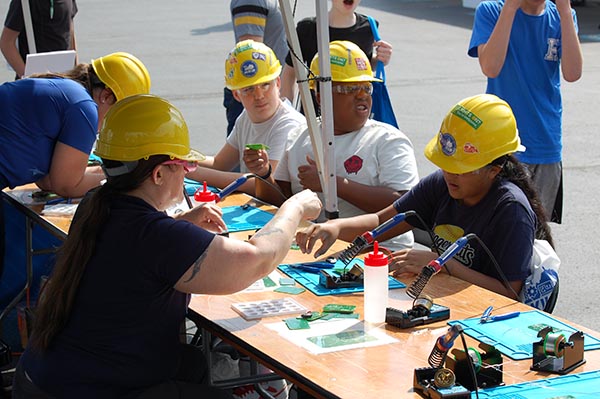 Students sitting around a table with hard hats on.